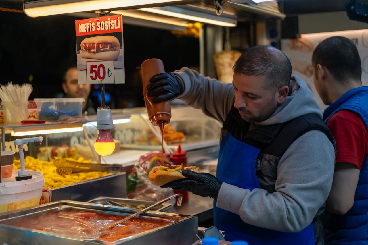 services-03 A street vendor serving hot dogs with sauce at a food stall in Istanbul, Turkey at night.